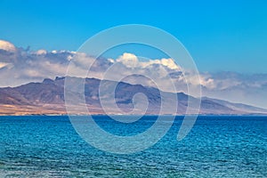 View of the hill on the island Fuerteventura near Morro Jable, Canary islands, Spain. There is clear blue water and beautiful sky