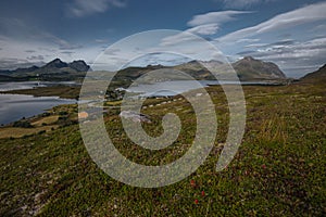 View from hill of the lake with view to mountains in the Norway at summer sunset