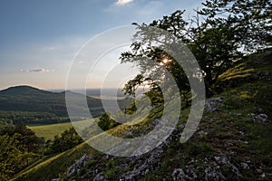 view of hill meadows and Spiš Castle in the Slovak Little Carpathian Mountains with the setting sun in the background