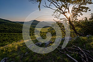 View of hill meadows and Spis Castle in the Slovak Little Carpathian Mountains with the setting sun in the background