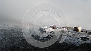 View from the hill top of a geological base with trailers and machinery. Clip. Foggy weather in mountains covered by