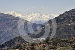 View of a Himalayan village on slop of mountain and snow capped mountain ranges