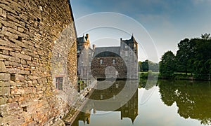 View of the historic Chateau Trecesson castle in the Broceliande Forest with reflections in the pond