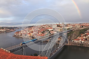 View of the historic city of Porto with the Dom Luis bridge, metro train and rainbow