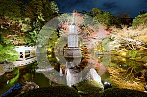 View of the Hojo Garden at Chion-in Buddhist temple. Pond, bridge, lantern and lots of green plants and trees in autumn evening