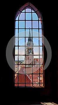 View on Holy Spirit Church and historical buildings through the stained glass window of Old Town Hall in Torun, Poland. August