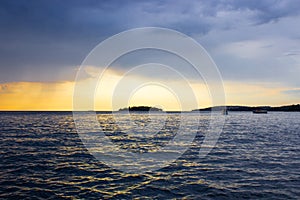 View of the horizon over the Adriatic Sea, with a boat sailing, during the sunset of a cloudy day while raining