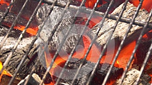 View of hot flaming charcoal briquettes glowing in the BBQ grill pit. Burning coals for cooking barbecue food. Close up