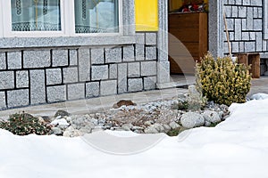 View of the house and the alpine hill with euonymus which appears from under the snow