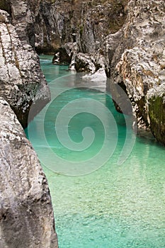 View on huge rocks in gorge canyon with turquoise green crystal clear river soca