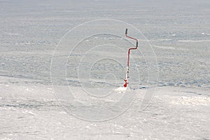 View of an ice drill in the lake ice. Drilling holes for winter fishing