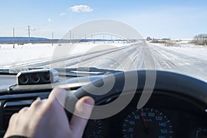 View of an icy, slippery road against the background of a car driver`s hand