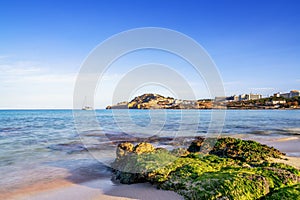 view of the idyllic bay and beach of Cala Agulla in eastern Mallorca with a sailboat in the foreground