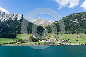 View of an idyllic and picturesque turquoise mountain lake surrounded by green forest and mountain peaks in the Swiss Alps