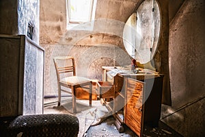 View inside an abandoned room with open wooden chest drawers and chair