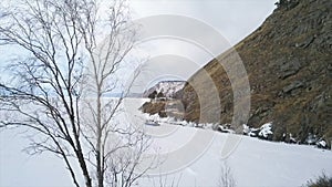 View from inside of arcuate tunnel on a frozen lake and the mountain. Clip. Aerial view of the icy water reservoir with