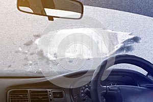 View from the inside of the car, during the first frost, through the powdered and frozen glass with ice. foreground and background