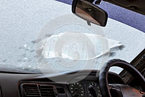 View from the inside of the car, during the first frost, through the powdered and frozen glass with ice. foreground and background