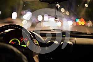 view from the inside of a car onto a metropolis street with bright lights from cars and advertising at night, blurred background