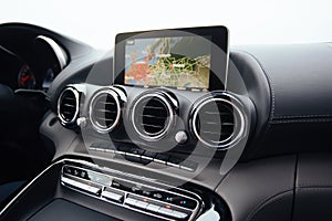 View from inside a car on a part of dashboard with a navigation unit and blurred street in front of a car