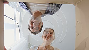 View from the inside of cardboard box as young smiling couple opening it