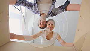 View from the inside of cardboard box as young smiling couple opening it