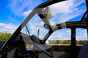 View inside classic French cult car 2CV on front seat, dashboard and steering wheel with open folding roof and windows against blu