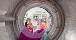 The view from inside the drum of a young woman and her daughter having fun doing housework, throwing more clothes into