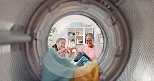 The view from inside the drum of a young woman and her daughter having fun doing housework, throwing more clothes into