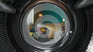 View from inside the empty washing machine with an opened door into the living room. Slow motion