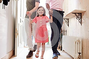 View Inside Hallway As Same Sex Male Couple With Daughter Open Front Door Of Home