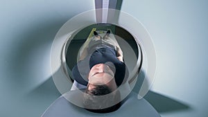 View from the inside of an MRI machine on a male patient moving out of it