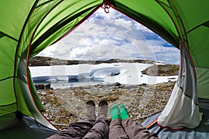 View from inside a tent on a beautiful nordic lake. Tourists lying in tent with a view of mountain landscape