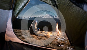 Male tourist have a rest in his camping in the mountains at night under beautiful night sky full of stars and milky way