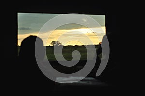 View from inside the train car to the beautiful natural landscape of sunset and trees. local train travel. selective focus