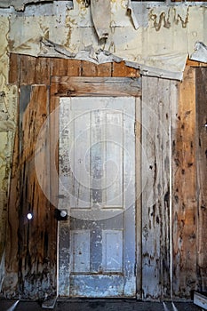 View of an interior doorway with rotting walls and decaying ceiling in Bannack Ghost Town in Montana