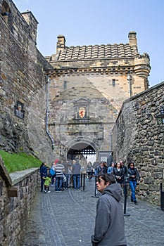 View at the interior Edinburgh Castle, detail of walls medieval fortress after principal gate, and tourists walking, on city of