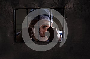 View through iron door with prison bars on male prisoner holding