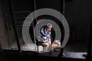 View through iron door with prison bars on male wearing prison u