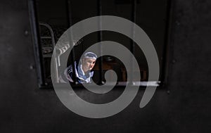 View through iron door with prison bars on man wearing prison un