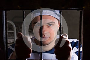 View through iron door with prison bars on young male prisoner h