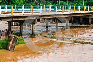View of irrigation canal with weeds and debris flowing together with strong flowing dirty brown water due to soil and mud from photo