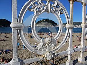 View of Isla de Santa Clara through the railing on Playa de la Concha, San Sebastian