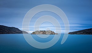 View of the island of Spinalonga with calm sea. Here were isolated lepers, humans with the Hansen`s desease, gulf of Elounda.