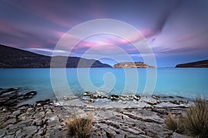 View of the island of Spinalonga at sunset with nice clouds and calm sea.