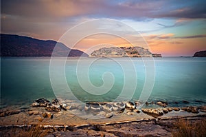 View of the island of Spinalonga at sunset with nice clouds and calm sea.