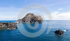 View at the islet of Mole and coast rocks, on village of Porto Moniz, formed by volcanic rocks, coast of the Madeira island,