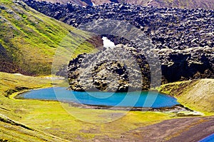 View on  blue crater lake with volcanic lava ash after eruption with green valley