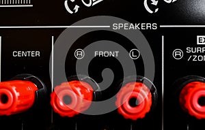 View on isolated red speaker outputs in a row of back side of black dolby surround home cinema receiver