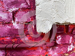 View on isolated rough brick wall painted in white, pink, purple and white color with water pipe Focus on white wall right